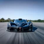 Ein schwarzer Bugatti Bolide Hypercar rast über eine Rennstrecke, mit Bewegungsunschärfe, die seine hohe Geschwindigkeit betont.