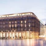 Visualisierung der Fassade des Althoff Dom Hotels in Köln bei Abenddämmerung. Das historische Gebäude ist elegant beleuchtet, und auf der Dachterrasse genießen Gäste den Ausblick.