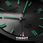 Nahaufnahme der Tissot PRC 100 Solar Uhr mit schwarzem Zifferblatt und grün leuchtenden Indizes und Zeigern, welche durch Super-LumiNova® bei Dunkelheit gut sichtbar sind.